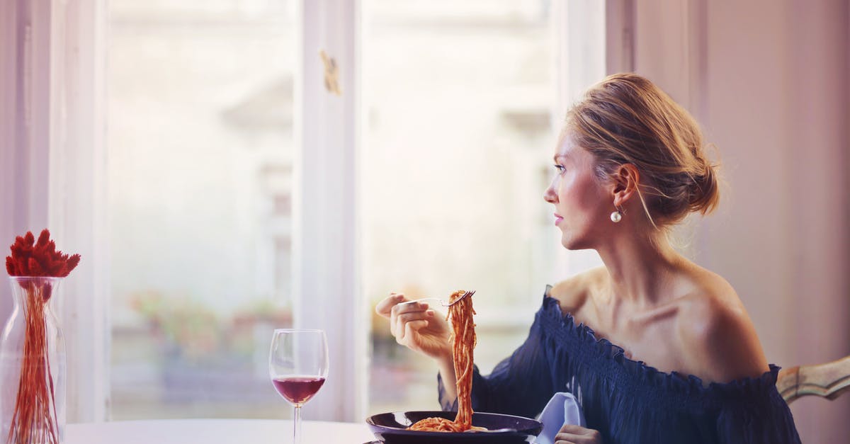 How should red wine be used in Spaghetti Bolognese? - Woman Sitting on Chair While Eating Pasta Dish