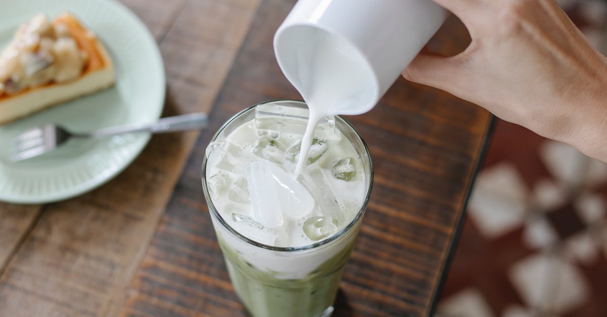 How to add alkaline to a drink? - Crop unrecognizable woman adding milk to iced matcha tea