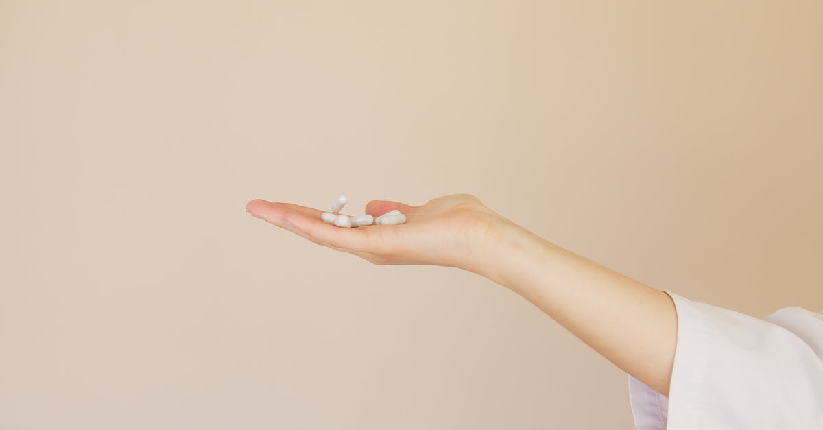 How to add flavour coating to gelatine or starch capsules? - Crop female pharmacist with pile of white pills on palm