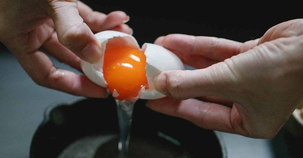 How to add panko to chicken without frying the chicken? - Crop anonymous chef breaking raw chicken egg in pan against dark blurred background