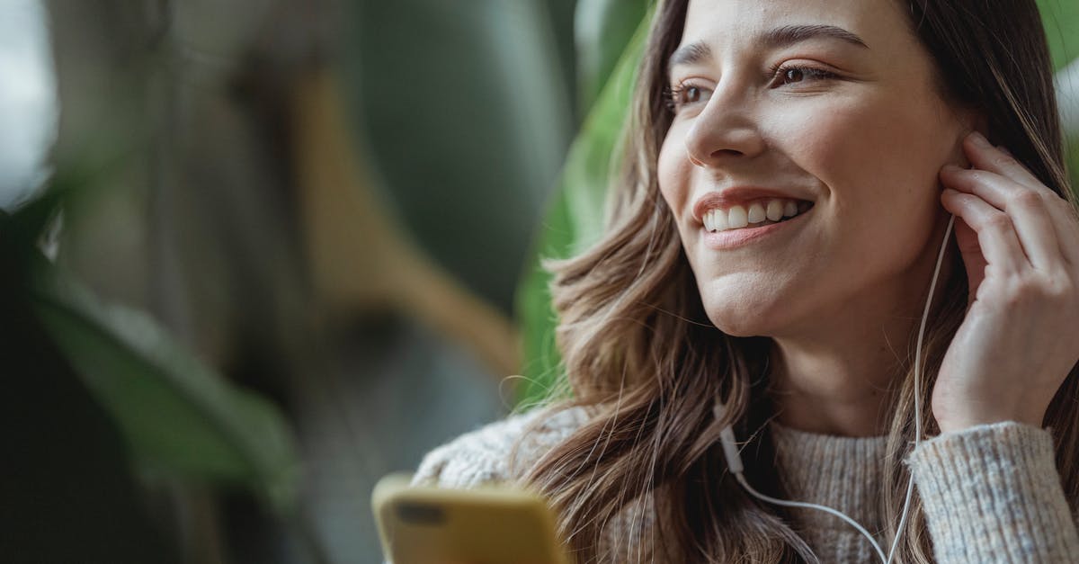 How to adjust time for oven stuck at 350F - Happy young woman with long wavy hair smiling and adjusting earphones while listening to music via mobile phone