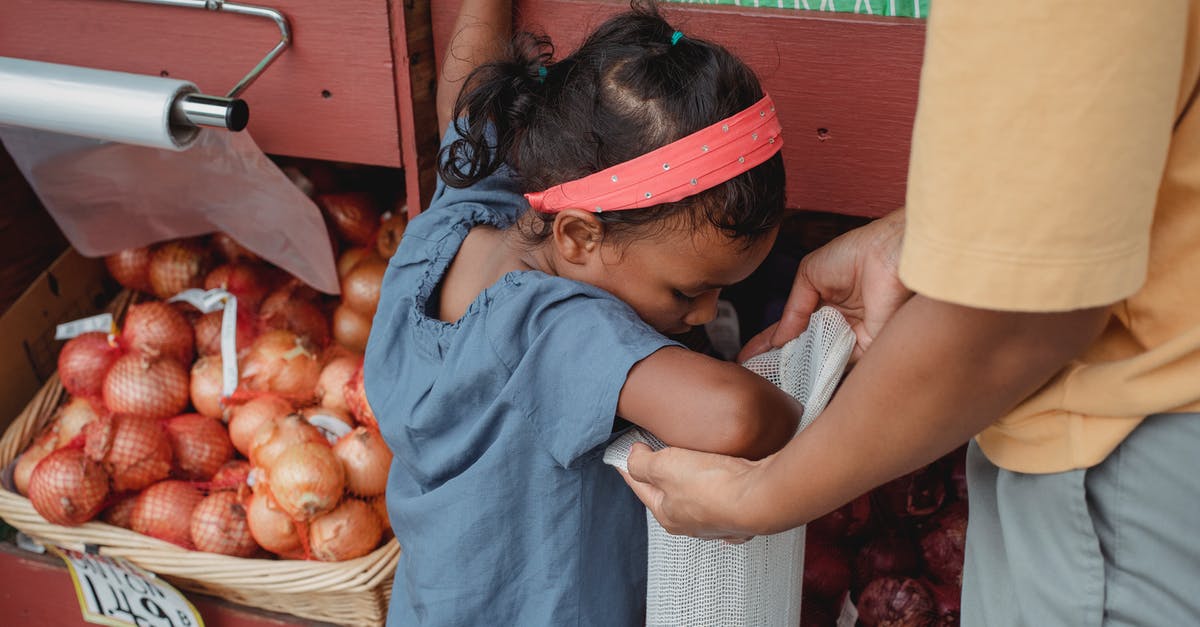 How to authenticate food products? - Asian girl buying vegetables with mother in local street market