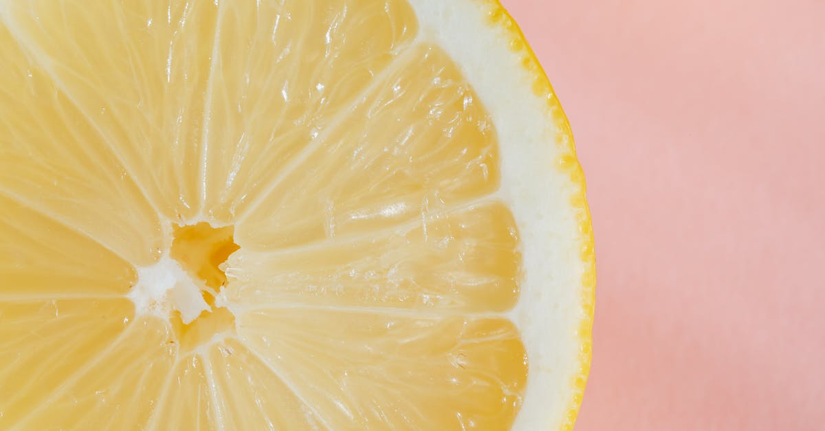 How to avoid 'fake tasting' fruit - Closeup of slice of fresh juicy bright lemon placed on smooth pink surface