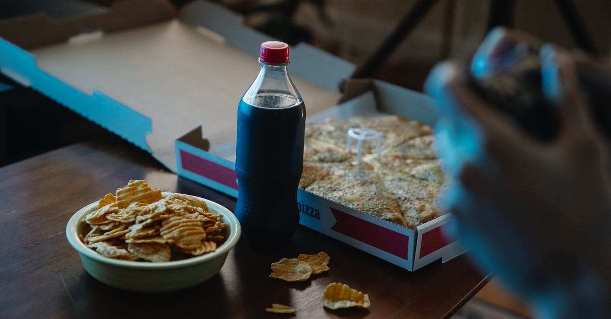 How to bake baking soda to produce sodium carbonate? - Crop person at table with potato chips and cola