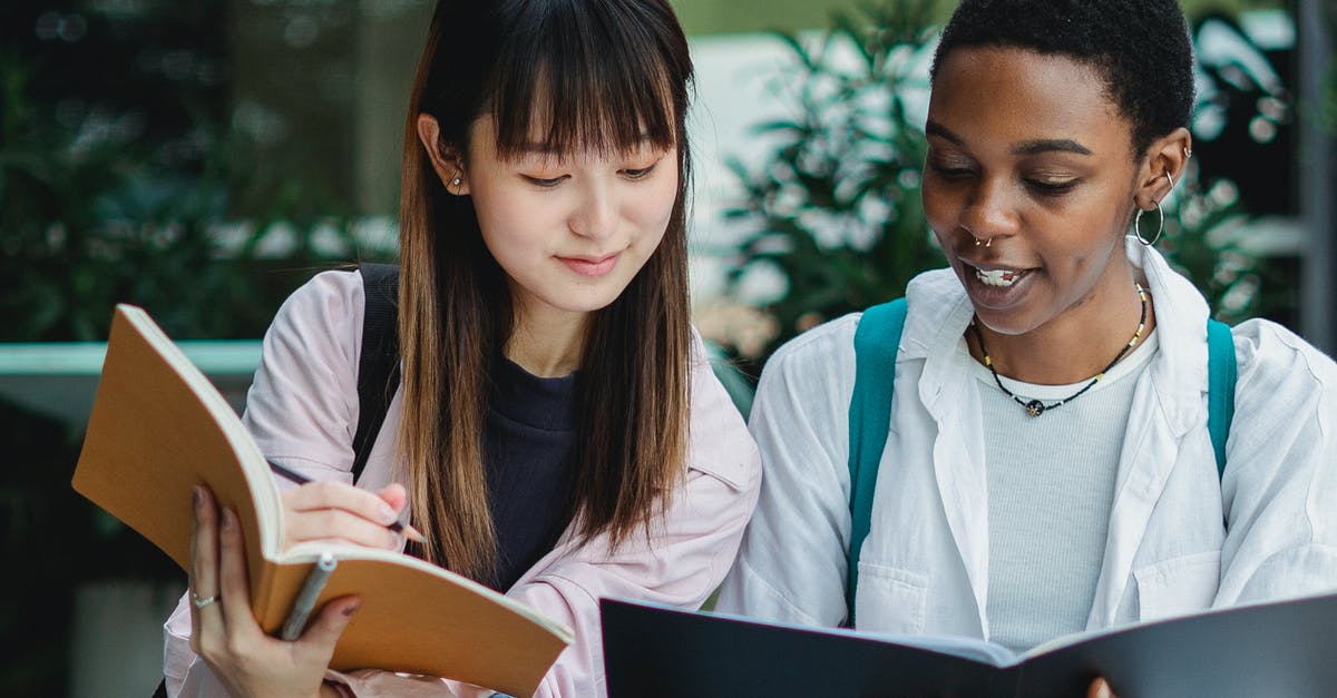 How to best prepare Sukimono - Young smiling black female student with exercise book talking to Asian partner on street in daylight