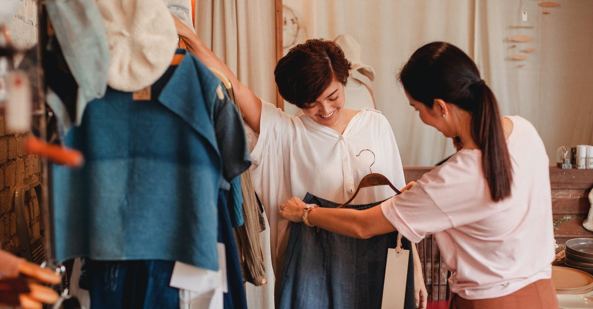 How to best store cupcakes? - Unrecognizable woman showing clothes to cheerful Asian girlfriend in shop