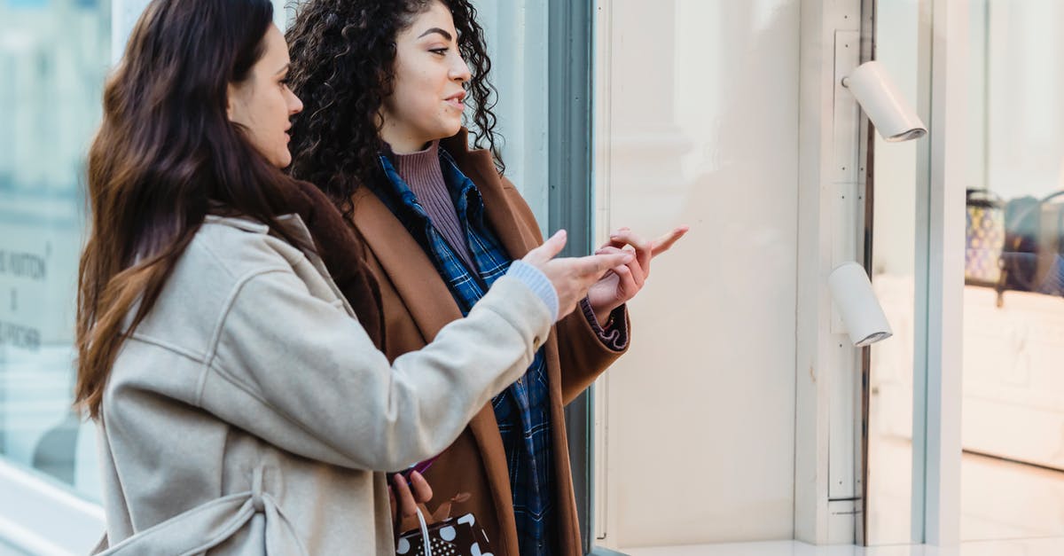 How to best store scallions? - Side view of positive young multiracial female friends standing on city street and pointing on showcase of fashion boutique during shopping