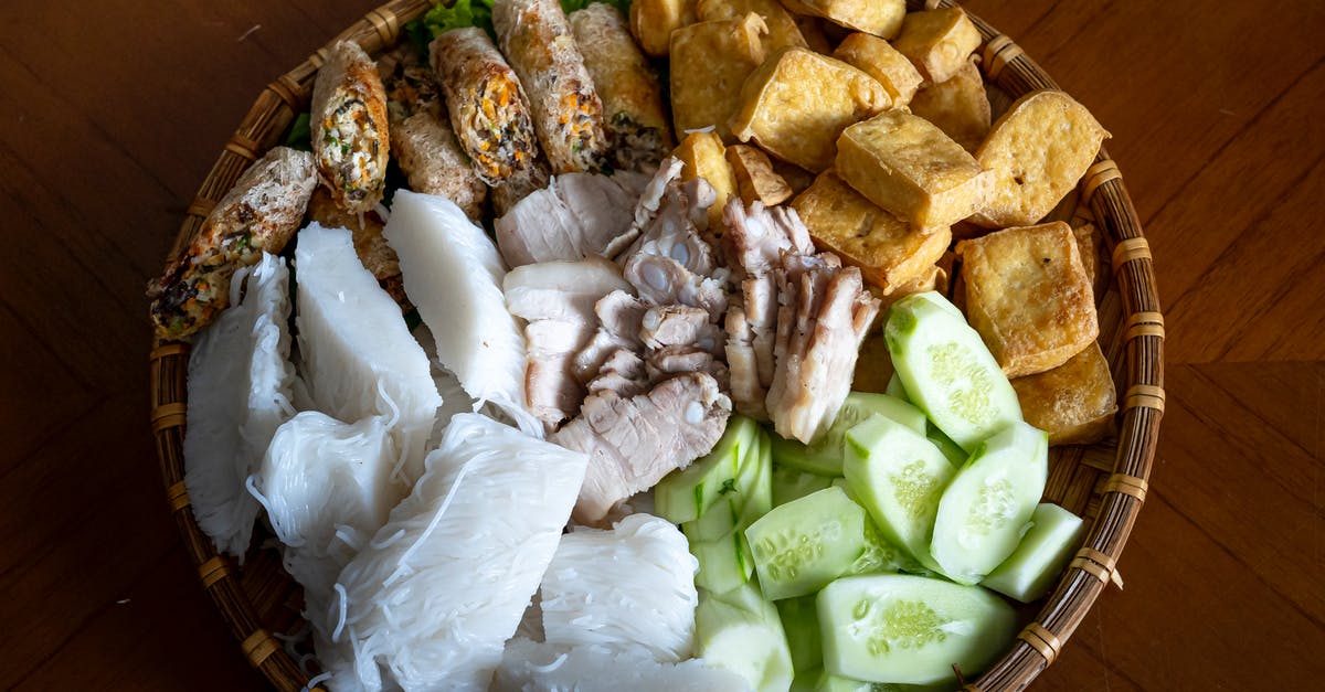 How to boil pork knuckle? - Top view of Asian food with rice noodles cucumber fried tofu and boiled pork with springs rolls served in bowl on table