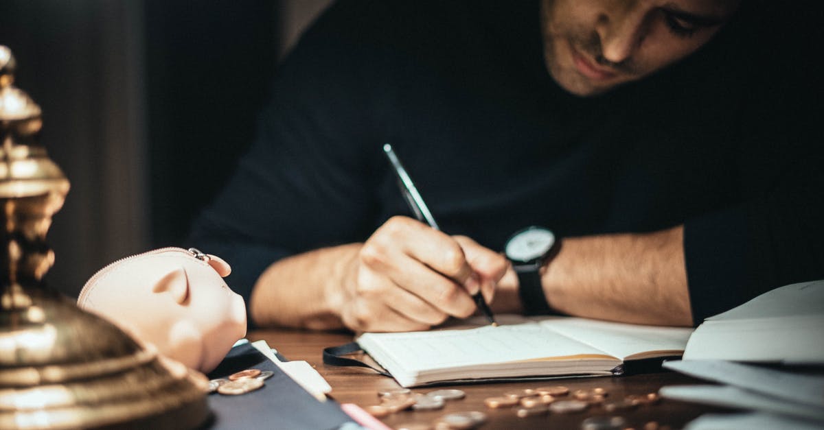 How to Calculate Scoville Heat? - Crop elegant man taking notes in journal while working at desk with coins and piggybank in lamplight