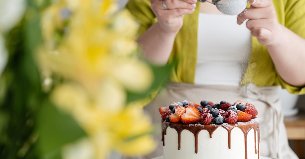 How to change this frosting recipe to get a thicker result? - Crop female baker strewing powdered sugar to decorated cake