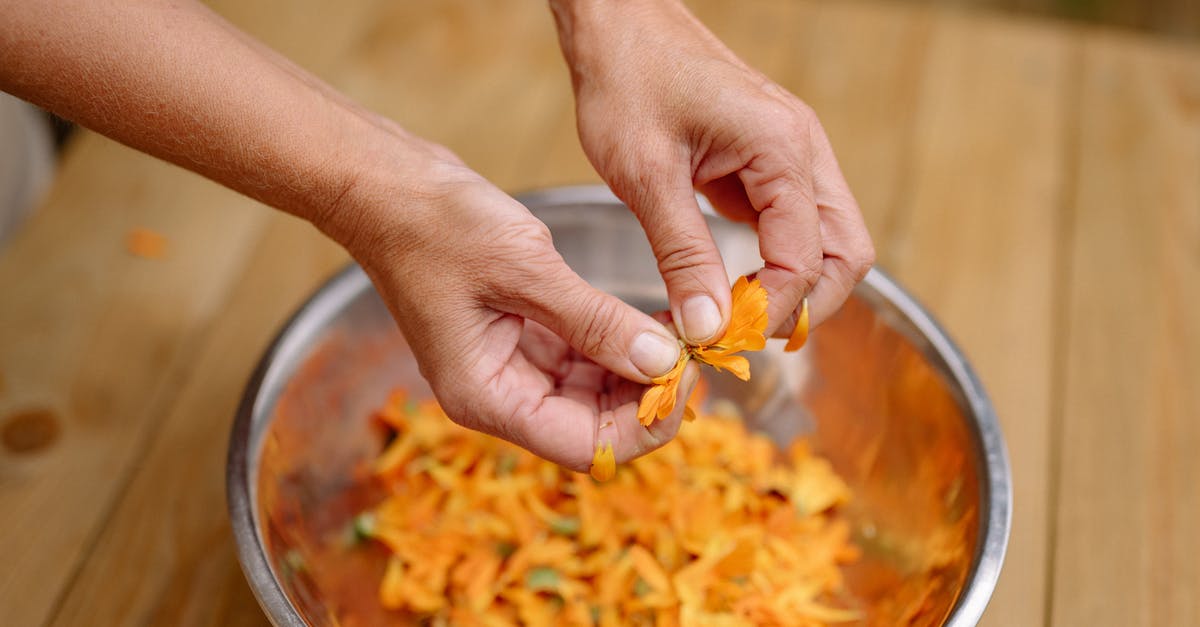 How to (cheaply) maintain a plentiful herb supply - Woman Tearing Orange Petals into a Metal Bowl