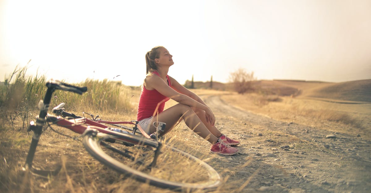 How to chill a compote? - Full body of female in shorts and top sitting on roadside in rural field with bicycle near and enjoying fresh air with eyes closed