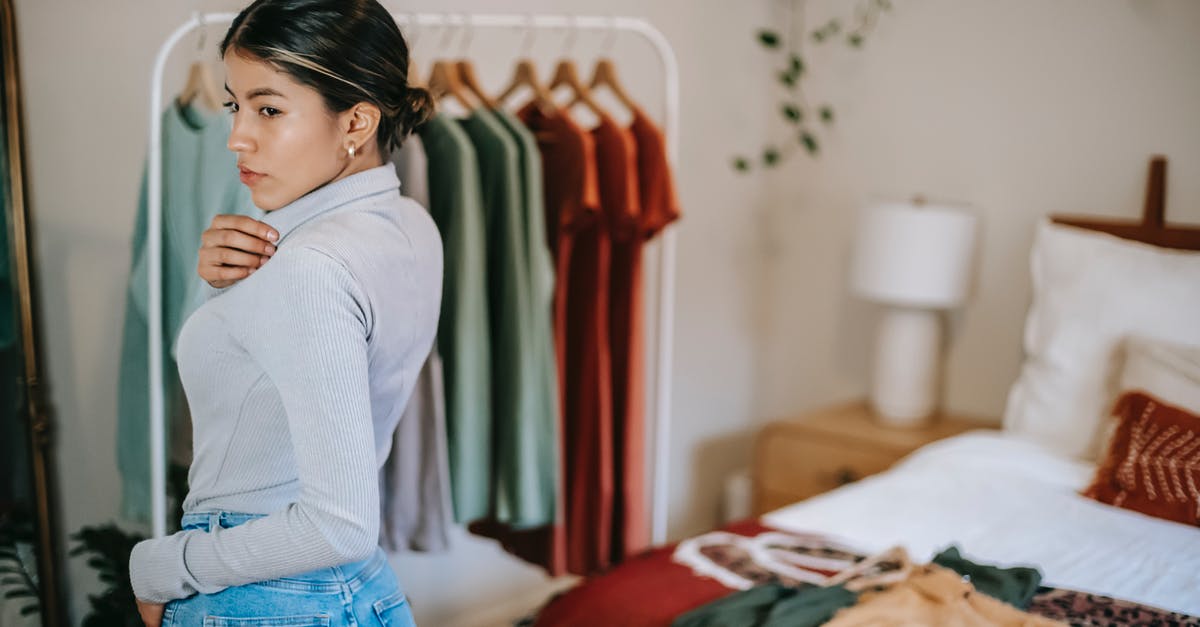 How to choose an upright, self-defrosting freezer? - Side view of confident ethnic woman in trendy outfit demonstrating outfit in bedroom near bed and wardrobe near mirror at home