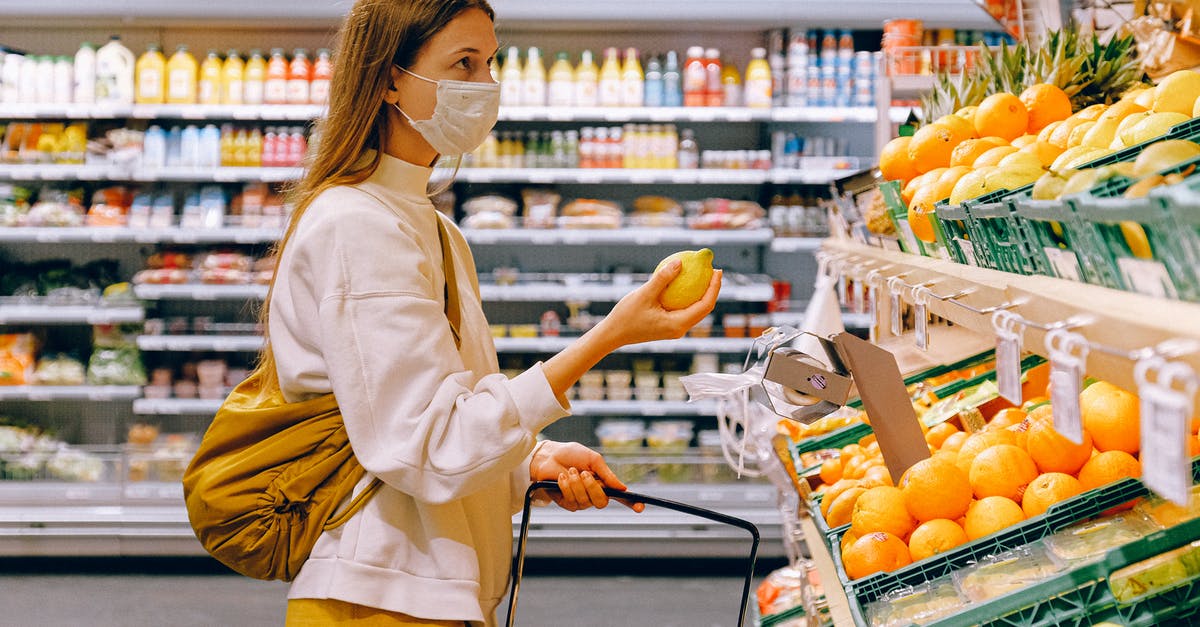 How to choose coconut in supermarket? - Woman in Yellow Tshirt and Beige jacket Holding a Fruit Stand