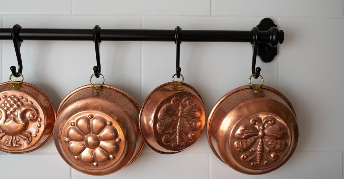 How to clean a copper kettle? - Old-Fashioned Copper Baking Pans Hanging on Wall in Kitchen