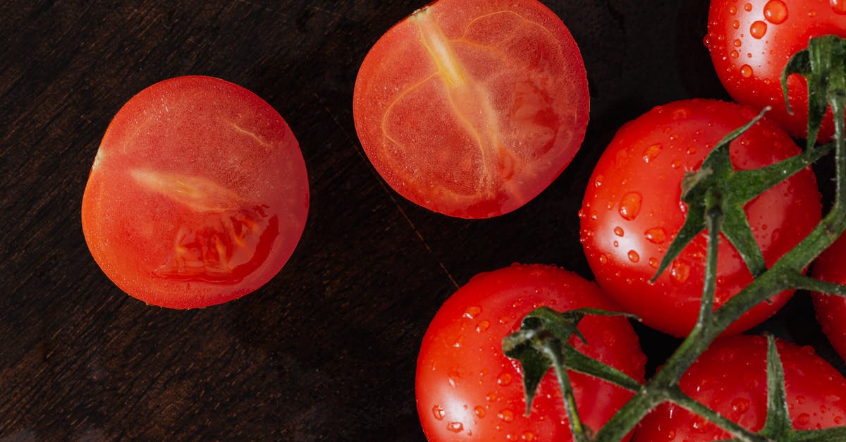 how to clean a tomato [duplicate] - From above closeup of cut on halves fresh tomato and branch of ripe tomatoes with drops placed on wet wooden cutting board