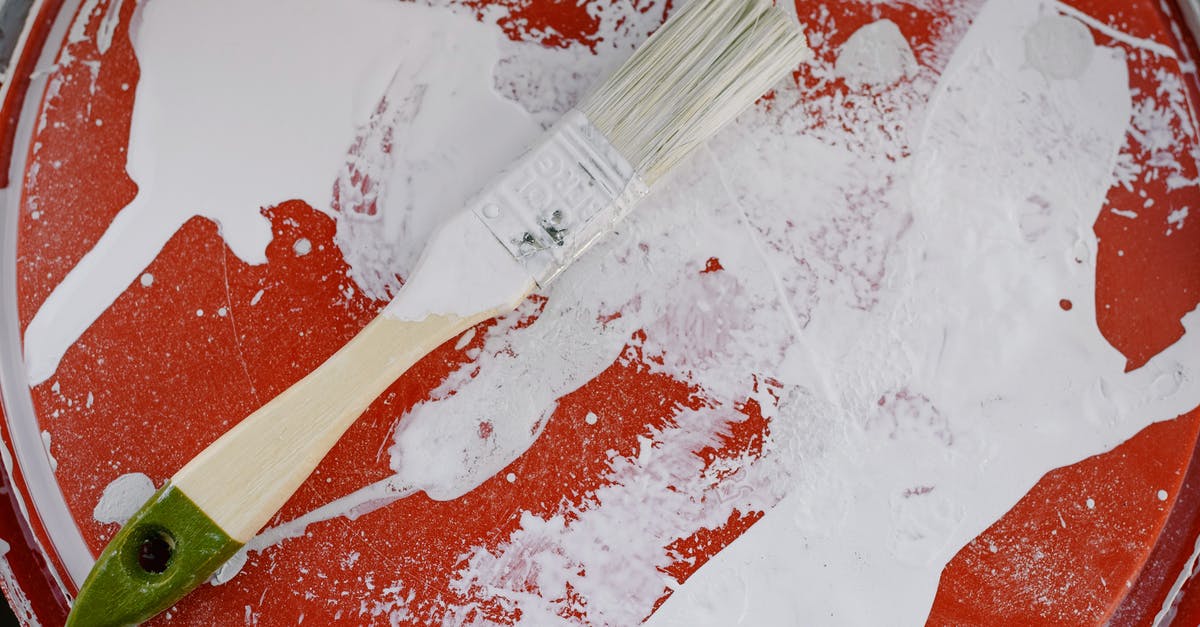 how to clean ginger residue from my plastic juicer containers? - From above of brush with white paint on dirty plastic surface during repair