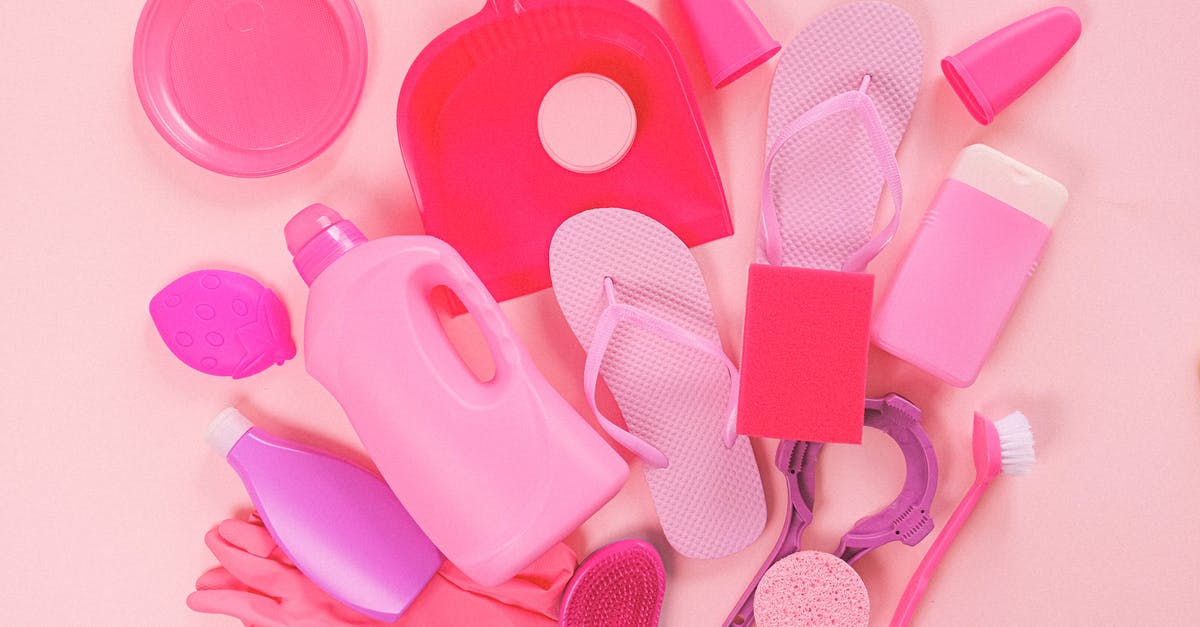 How to clean molten plastic from a pizza stone? - Collection of various plastic detergent bottles and cleaning tools placed on pink background near flip flops and rubber gloves