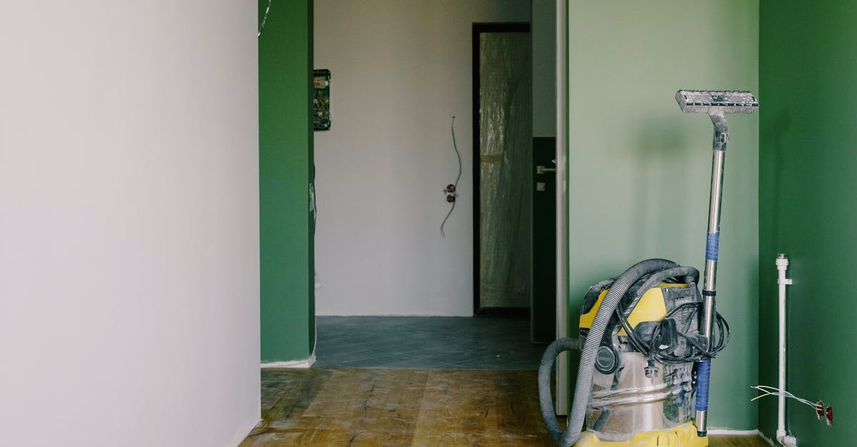 How to clean stains from inside of vacuum flask? - Industrial vacuum cleaner placed on dirty parquet in room with green walls and doorway in spacious apartment during repair works