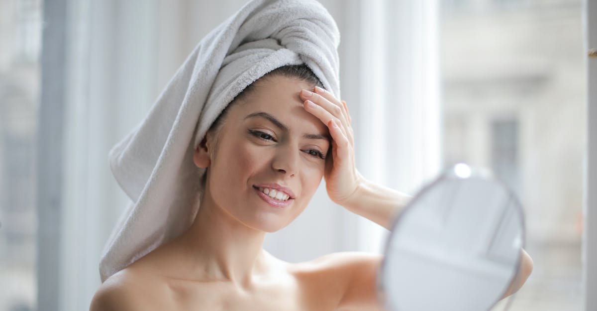 How to clean the rubbery skin from monkfish before cooking? - Selective Focus Portrait Photo of Smiling Woman With a Towel on Head Looking in the Mirror