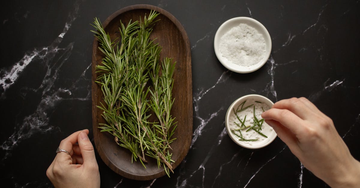 How to clean up the smell of egg from a pot? - Top view of unrecognizable woman adding fresh twigs of rosemary in bowl with salt for organic scrub placed on black marble table