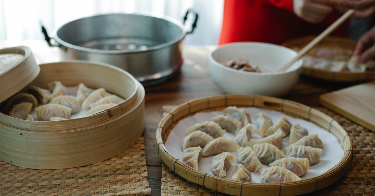How to color Jiaozi (chinese dumplings)? - High angle of crop anonymous female folding dumplings while preparing traditional Chinese jiaozi in kitchen at home