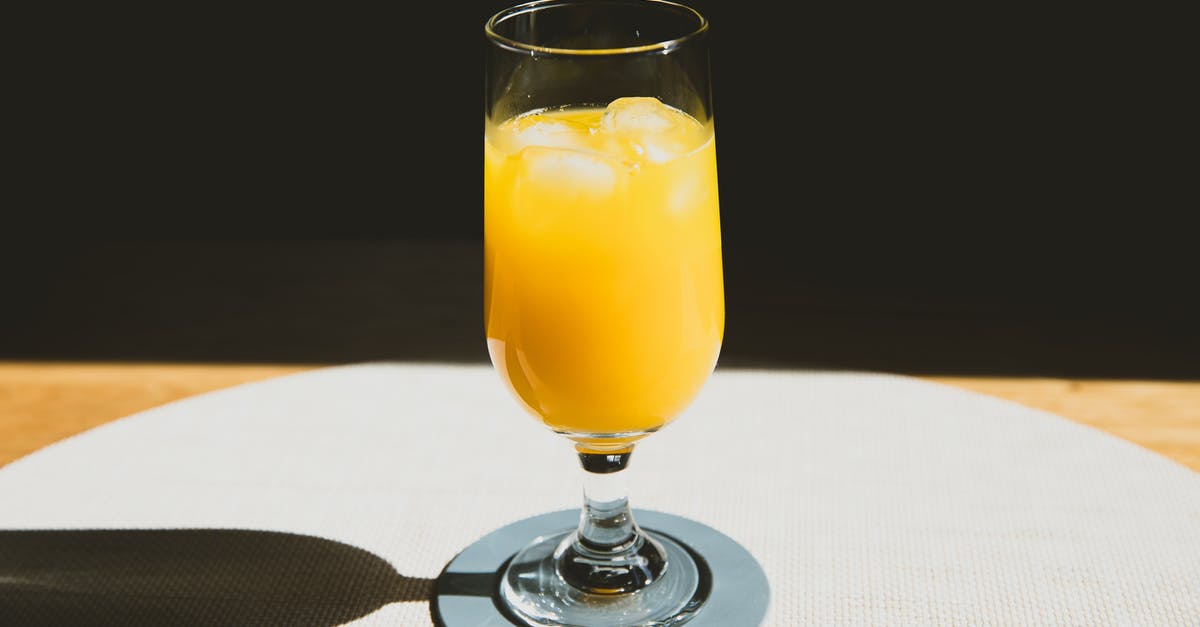 How to conserve natural fruit juices without alcohol? - Crystal glass of cold refreshing orange juice with ice cubes placed on table