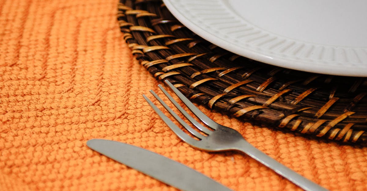 How to convert knife edge angle "ratios" into degrees? - Closeup of fork and knife on orange tablecloth with ornament under round plate on wicker mat