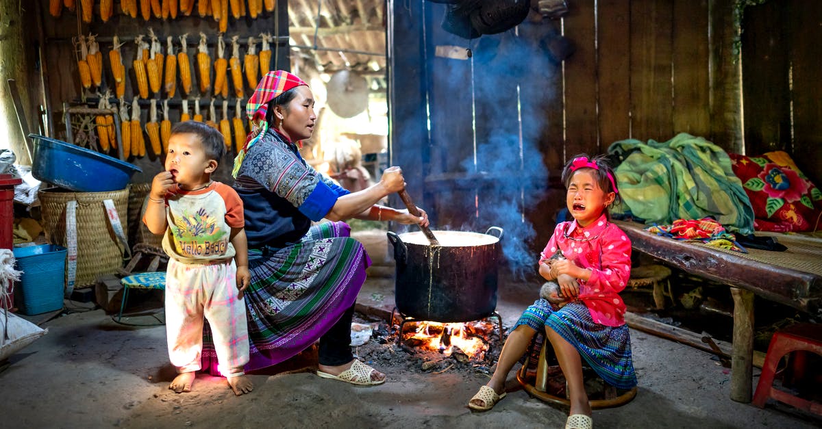 How to cook baby octopus? - Ethnic mother preparing food against crying girl and baby indoors