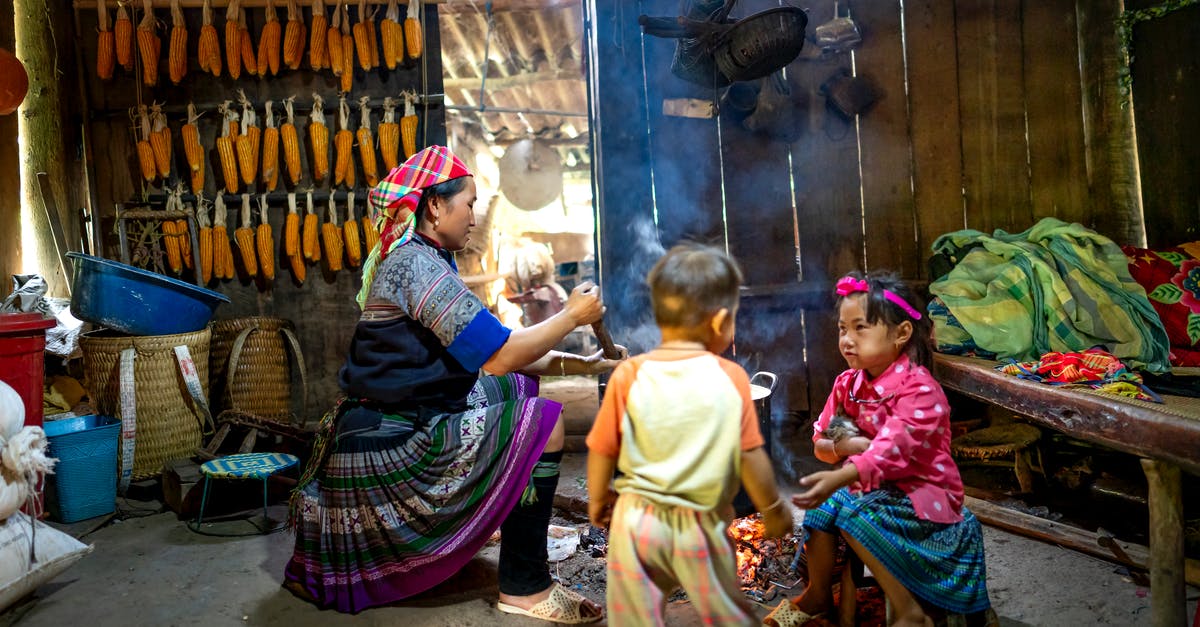 How to cook baby octopus? - Ethnic mom stirring food in pot against girl speaking with anonymous toddler brother in poor house