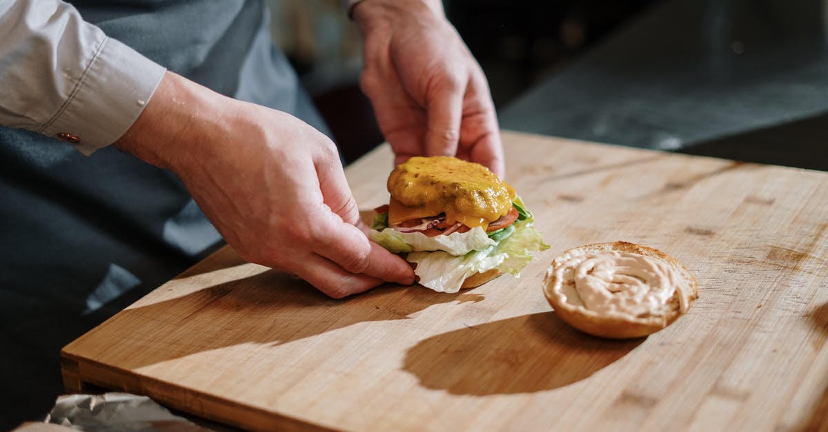 How to cook bison burgers (a.k.a. buffalo burgers)? - Person Holding Burger on Brown Wooden Chopping Board