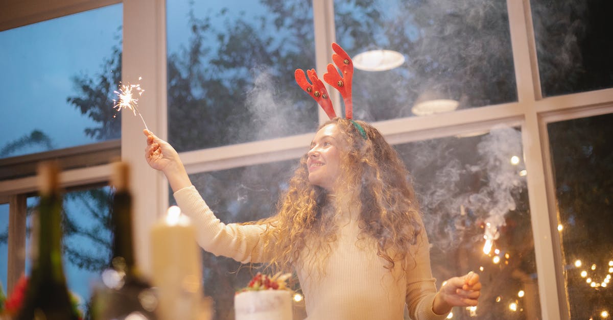 How to cook fallow deer ribs? - Content female chef in decorative deer horns with shiny sparkler celebrating New Year holiday while looking away in house