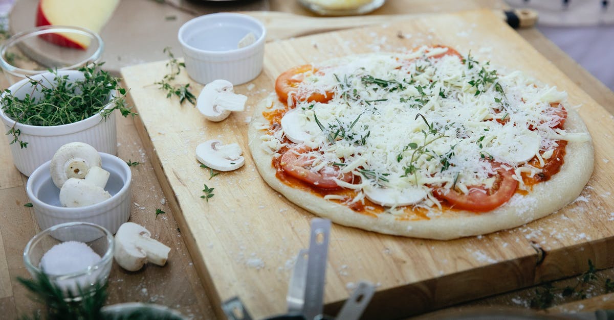 How to cook Parmesan Cheese into a broth without making globs? - From above of dough with tomatoes and champignons topped with cheese prepared for pizza on wooden board