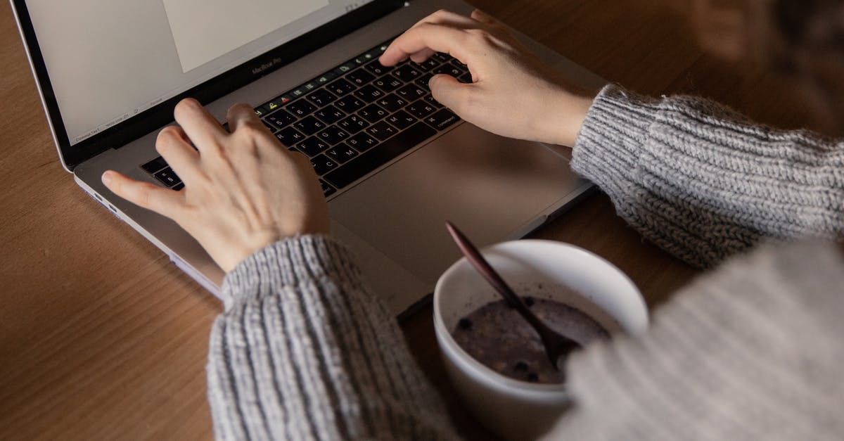 How to create a soup with frozen chicken? - From above unrecognizable woman in gray sweater sitting at wooden table with food in bowl and creating document while working on remote project at home