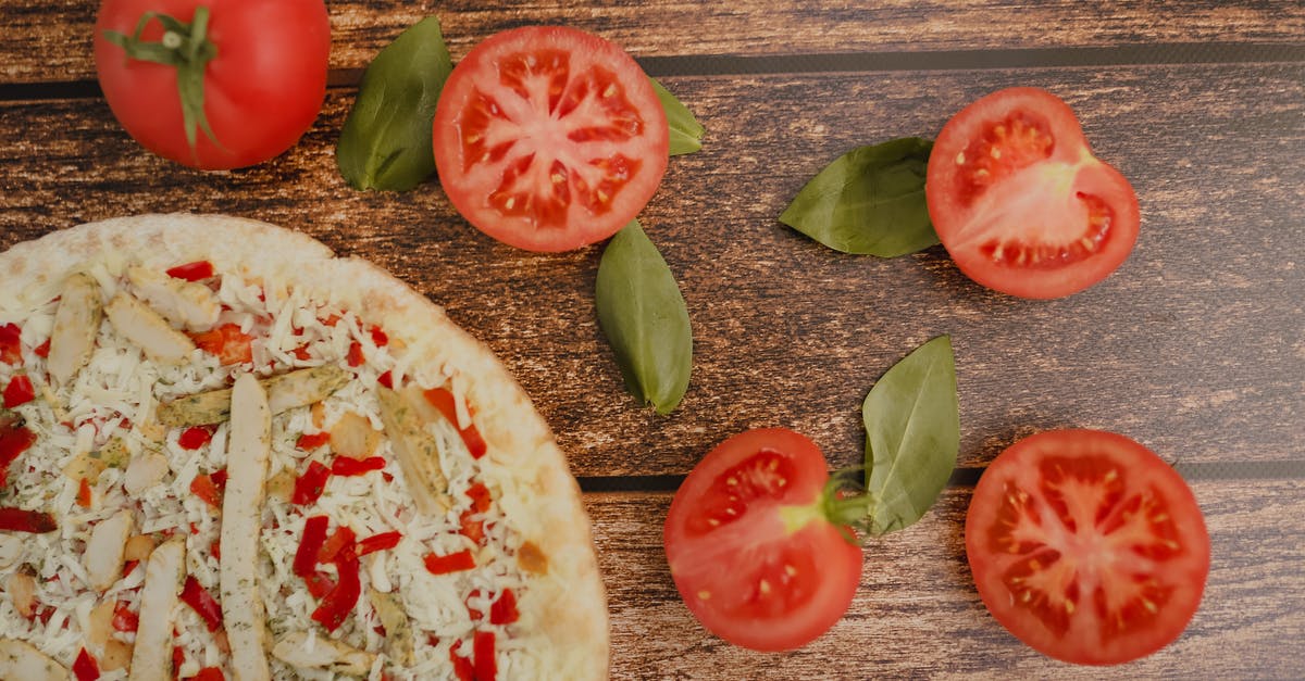 How to cut chicken without producing loud noises - Top view of tasty pizza with chicken slices and grated cheese near fresh cut tomatoes and basil leaves on wooden table