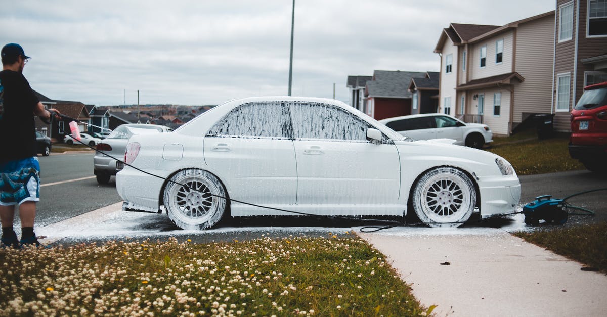 how to disarm a potentially pressurized whipping siphon? - Foamed car on driveway and sidewalk being washed by male driver at daytime