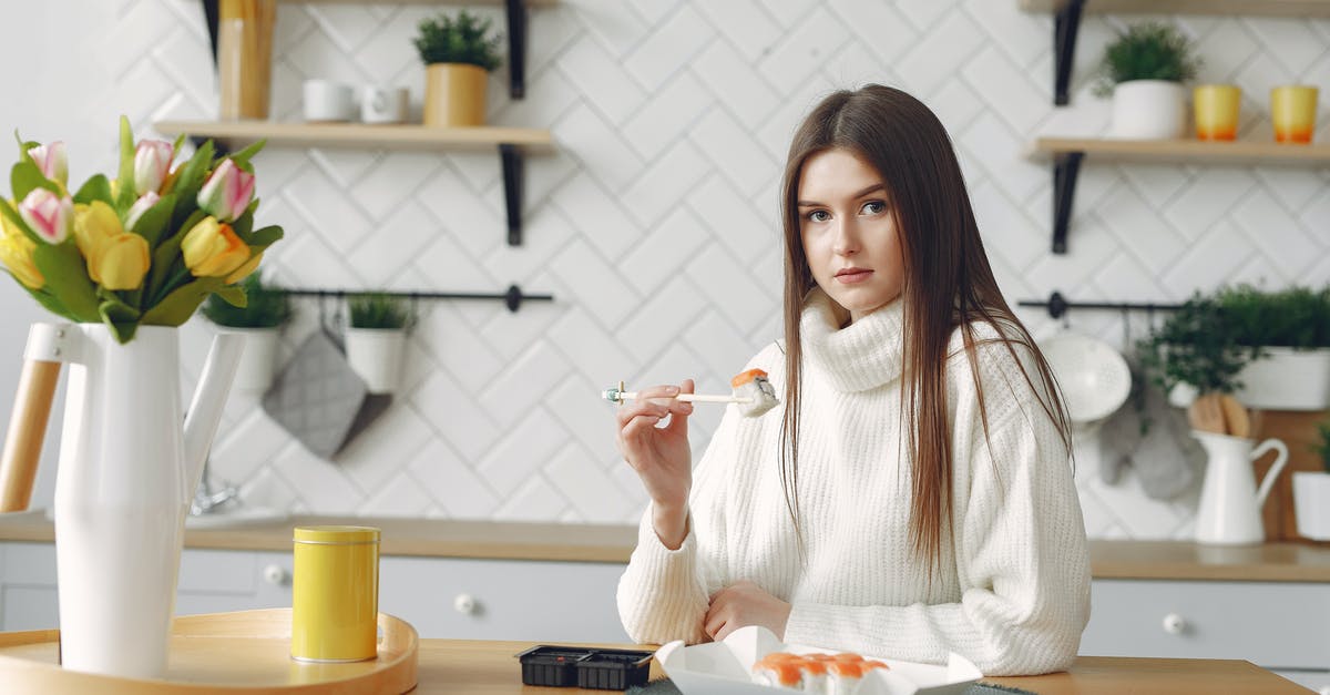 How to dress sushi to better enhance all its flavours? - Young female eating sushi in modern kitchen