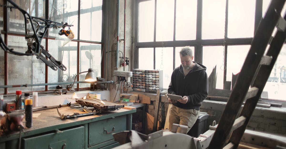 How to fix a bitter jam? (Or use it?) - Adult bearded mechanic in casual wear standing near window in workshop and browsing digital tablet