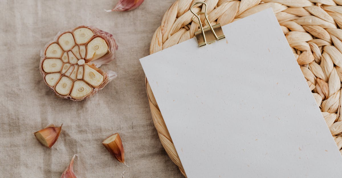 How to fix food that got extra salty? - Sheet of empty paper with clip put near halved garlic cloves