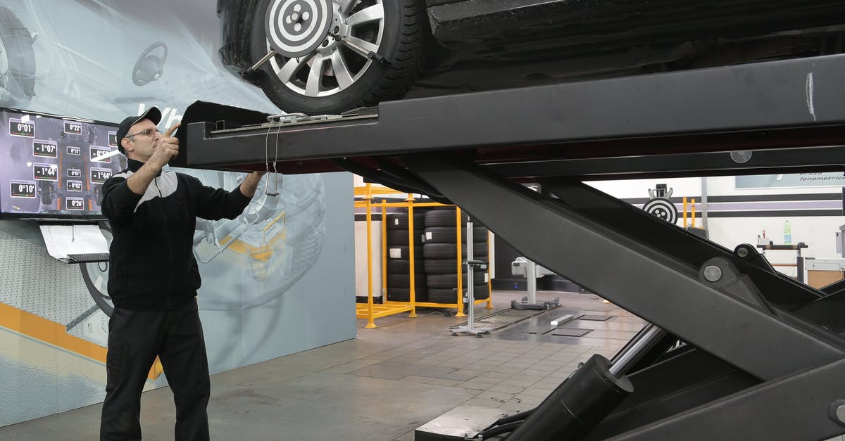 How to fix oily modeling chocolate - Serious mechanic checking car wheels on lift in modern car service garage