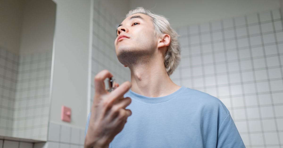 How to get a good fragrance from burnt rosemary? - Man in Blue Crew Neck T-shirt Applying Perfume