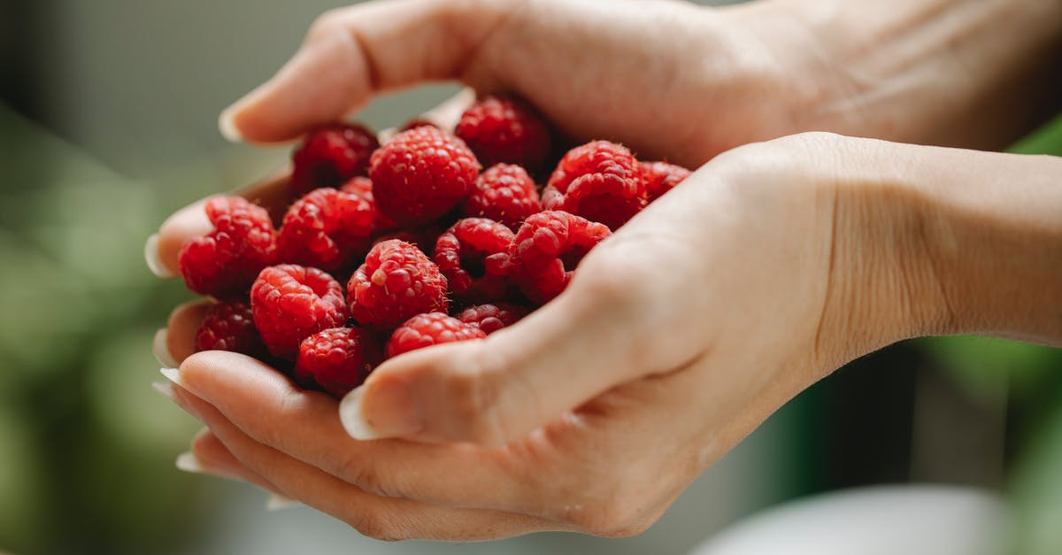 How to get raspberry flavor into a smoothie without seeds? - Crop woman with raspberries in hands