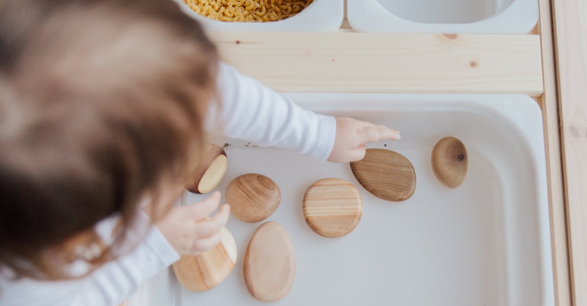 How to get rid of chili-peppers on fingertips? - Crop anonymous child getting brown stones from white container at home