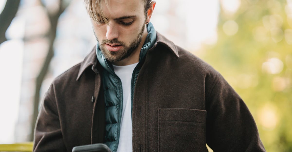 How to get rid of chili-peppers on fingertips? - Young hipster looking at smartphone screen in park