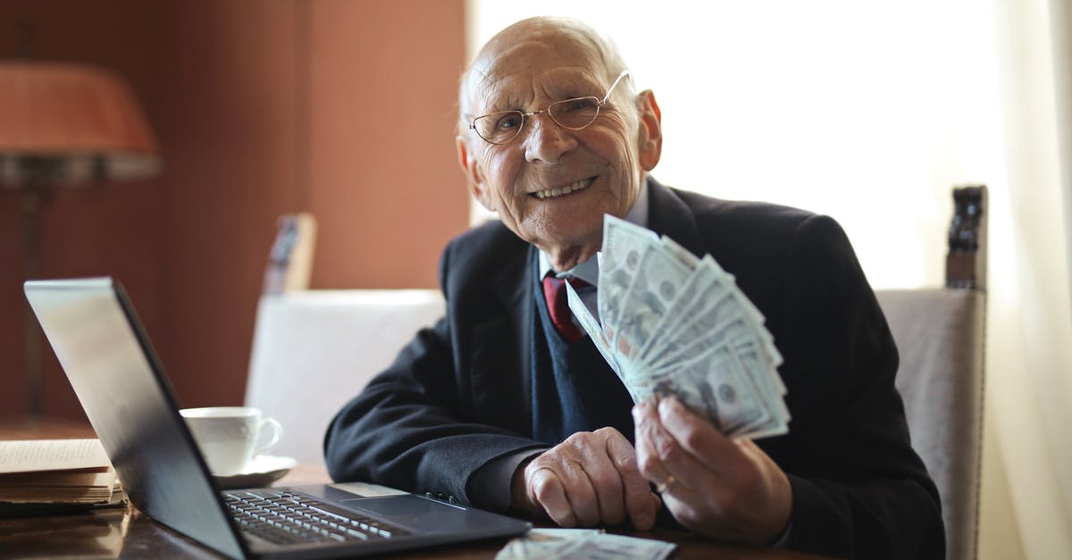 How to get those professional looking peaks on top of tiramisu? - Happy senior businessman holding money in hand while working on laptop at table