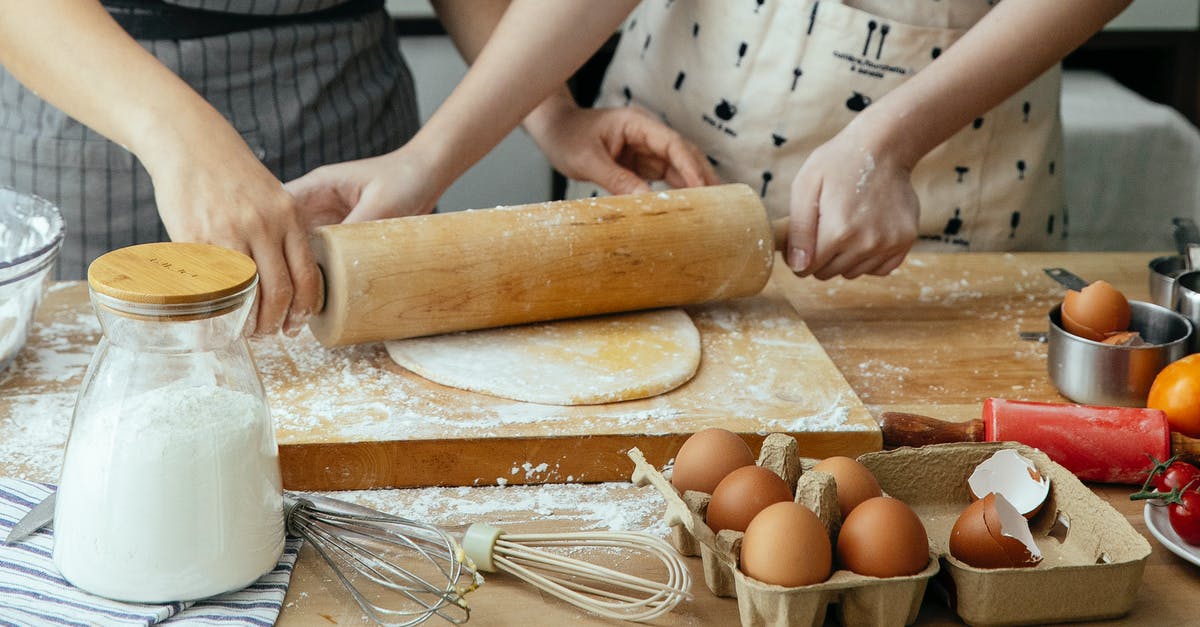 How to get threads in a yeast dough? - Unrecognizable women rolling dough together on board on table with jar with flour carton with eggs and whisks