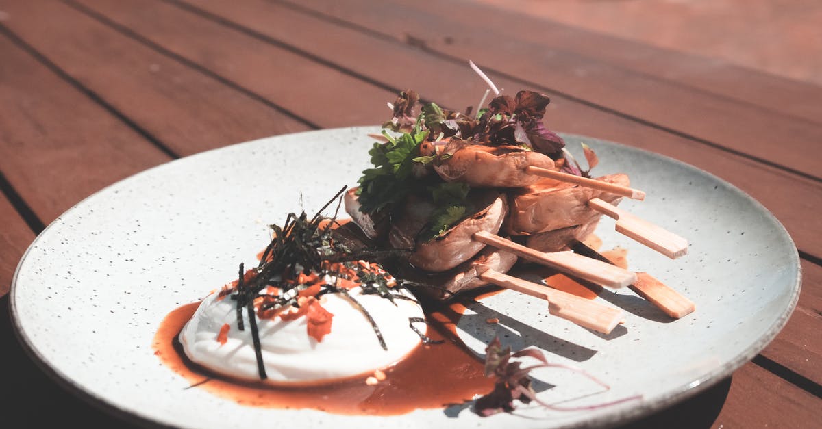 How to have my solar system stick that would be edible - Fresh cooked meat on skewers near poached egg and herbs with sauce on plate on wooden table in terrace in daylight