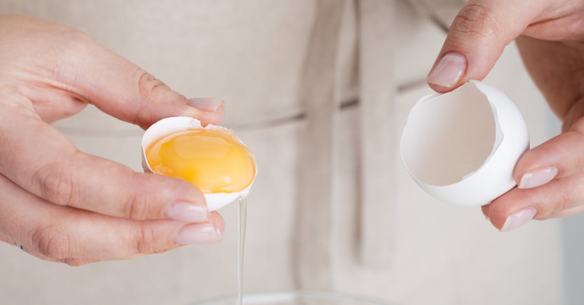 How to hold and then poach egg yolks? - Close-Up Shot of a Person Holding a Cracked Egg