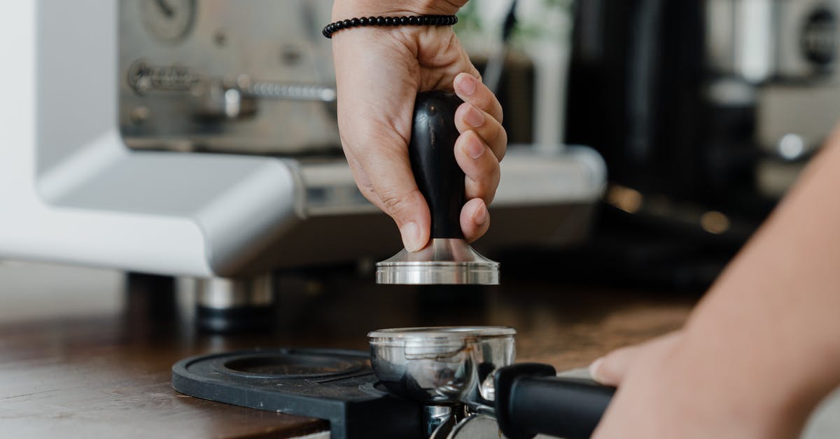 How to interpret "an ounce of ground coffee" - Unrecognizable female bartender pressuring ground coffee in portafilter with tamper for preparing tasty aromatic espresso during work in coffee house