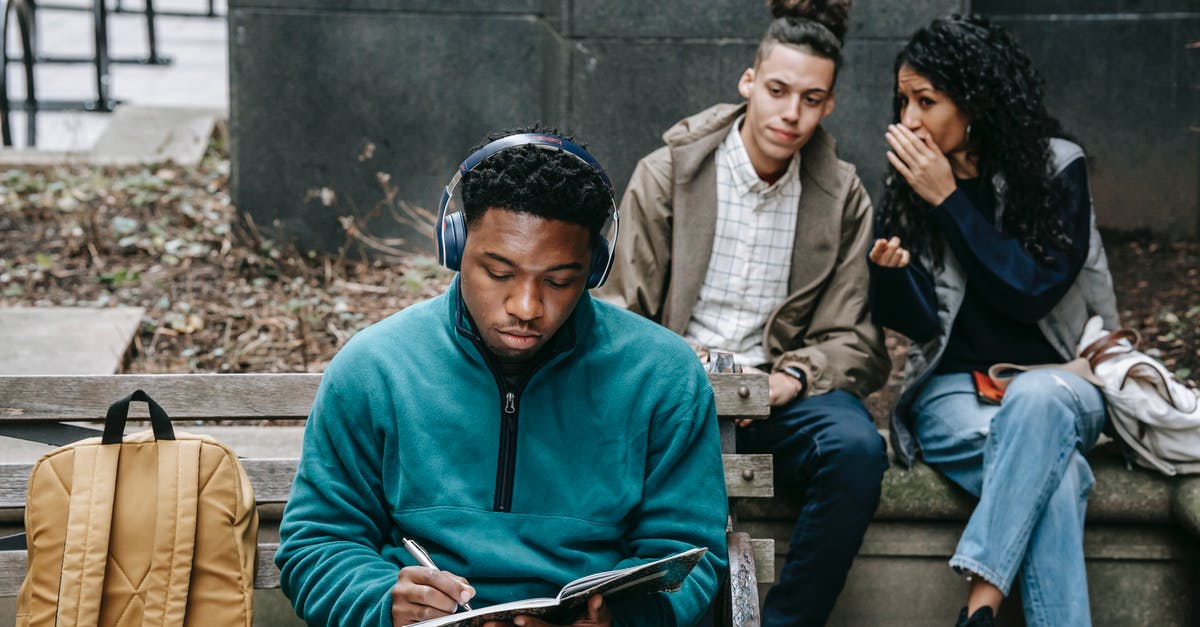 How to judge temperature and time for deep-fried turkeys? - Young multiethnic friends in casual outfit with backpack gossiping behind back of African American guy sitting on bench in headphones and taking notes in notebook in city street in daylight